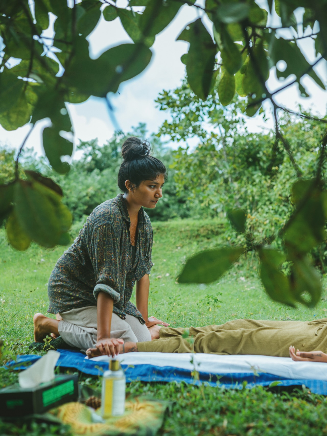 Kiranmayi practising bodywork on a mat in a garden