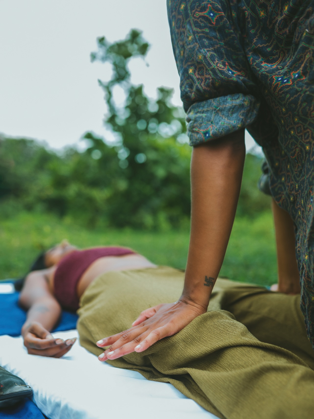 Kiranmayi applying pressure to a client's leg during an outdoor massage